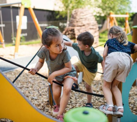 A group of small nursery school children playing outdoors on playground.